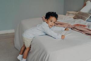 Sweet little african american kid boy playing in cozy bedroom at home photo