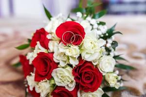 bouquet of red and white roses with wedding rings photo