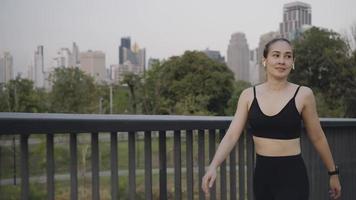 jonge vrouw in sportkleding glimlachend en weglopen tijdens het luisteren naar muziek in draadloze oortelefoons tijdens fitnesstraining. video