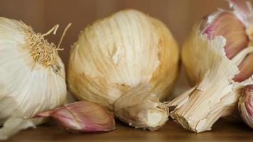 Close up of garlic bulbs on rustic table. Pan shot. video