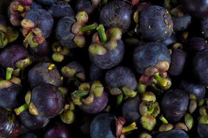 Above view of mangosteen fruit stacked together for sale. Background and textured of natural fruit of Thailand. photo