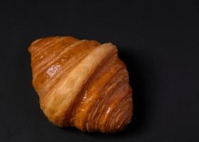 Fresh croissants bread and a cup of coffee on black background. photo