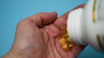 A man pours a capsule of fish oil in his hand. Omega 3 close-up. video