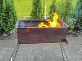 preparando barbacoa barbacoa fogata y quemando madera con llamas naranjas. foto