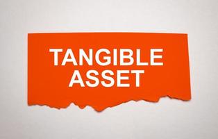 Tangible Asset. Text on red torn paper on grey background photo