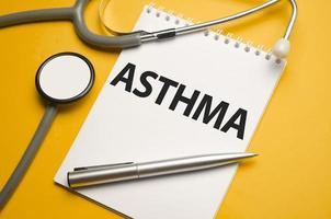 On a orange background, an open notebook with the word ASTHMA photo