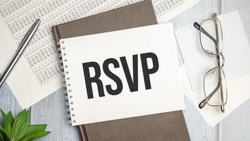 Text RSVP on paper on light background with pen and glasses. photo