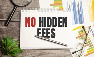 No Hidden Fees text written on black notebook with magnifying glass and a pen photo