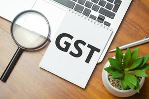GST word on notepad and laptop on wooden background photo
