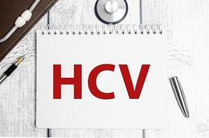 hcv word on white notebook and pen with stethoscope photo