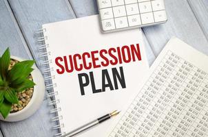 Notepad with text SUCCESSION PLAN on business charts and pen