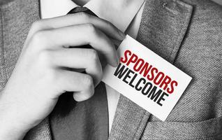 Businessman putting a card with text Sponsors Welcome in the pocket photo