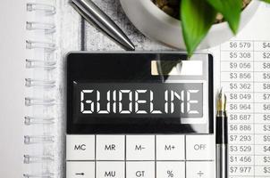 guideline word on calculator display and pen on charts photo