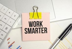 wORK SMARTER word on sticker on notepad with pen and calculator photo