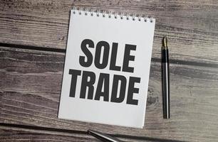 sole trade on notebook and pen on wooden background photo