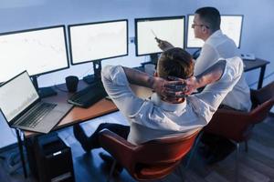 Talking with each other. Two stock traders working in the office with exchange technology photo