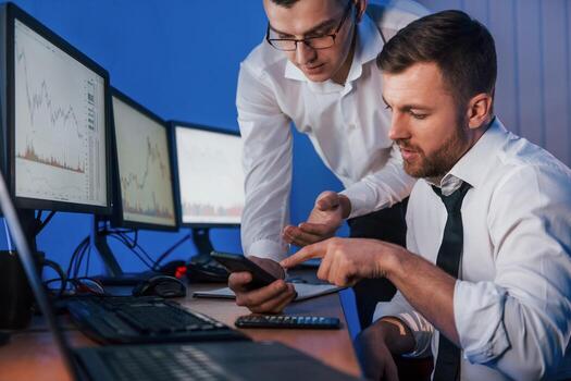Different information on screens. Two stock traders working in the office with exchange technology photo