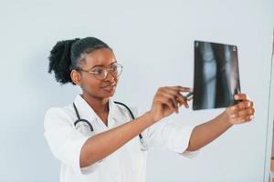 radiografía con imagen de huesos. joven mujer afroamericana está contra el fondo blanco foto