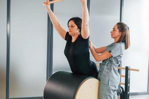 Stretching exercise. Woman is in health center getting help by doctor photo