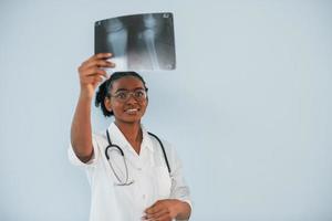 Holding x-ray. Young african american woman is against white background photo