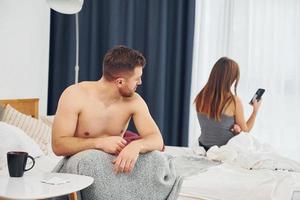 Conception of bed problems. Disappointed woman sitting with back to the man that feels bad photo
