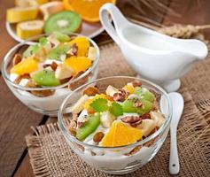 Healthy dessert with muesli and fruit in a glass bowl on the table photo