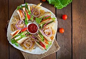 Club sandwich with cheese, cucumber, tomato, smoked meat and salami. Served with French fries. photo