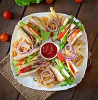 Club sandwich with cheese, cucumber, tomato, smoked meat and salami. Served with French fries. photo