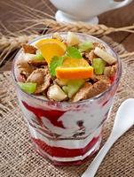 Healthy dessert with muesli and fruit in a glass bowl on the table photo