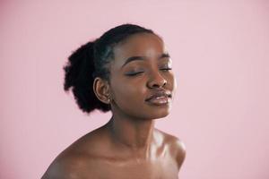 Portrait of young african american woman that is against pink background photo