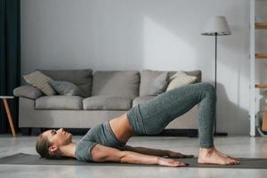 Stretching exercises. Young woman with slim body type and in yoga clothes is at home photo