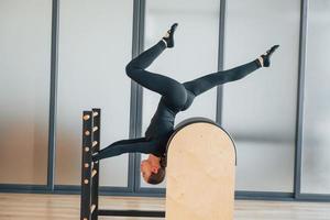 Doing tricks. Woman in sportive clothes is in the studio photo