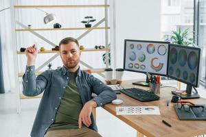 lanzando un avión de papel. diseñador masculino trabajando en la oficina usando pc foto