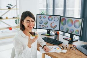 Talking by phone. Female designer working in the office by using PC photo