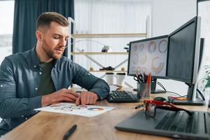 Paper with different colors. Male designer working in the office by using PC photo