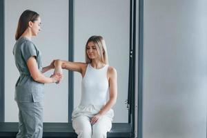 moviendo la mano. la mujer está en el centro de salud recibiendo ayuda del médico foto