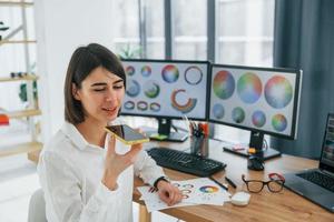 Talking by phone. Female designer working in the office by using PC photo