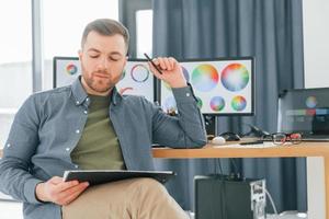 With tablet in hands. Male designer working in the office by using PC photo