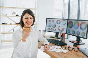 hablando por telefono diseñadora que trabaja en la oficina usando pc foto