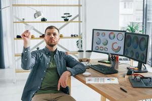 lanzando un avión de papel. diseñador masculino trabajando en la oficina usando pc foto