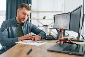 papel con diferentes colores. diseñador masculino trabajando en la oficina usando pc foto