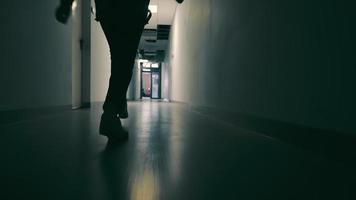 silhouette de jambes féminines qui membre sur un couloir sombre. femme va à une réunion légère au bout du couloir video