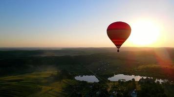 A balloon flies in the middle of the horizon at sunset. Picturesque picture of a balloon flying in the sun. Beautiful landscape dusk, balloon, lake and sunset video