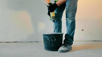 Plasterer painter construction worker mixes construction mixture in a bucket. Construction and renovation of the room. Indoor construction work. video