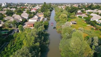 Flug über einen kleinen Fluss, der zwischen der Stadt fließt, und Motorboote, die Industriegüter liefern video