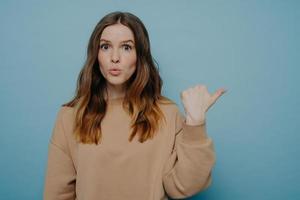 Surprised young woman pointing at copy space with wow expression photo