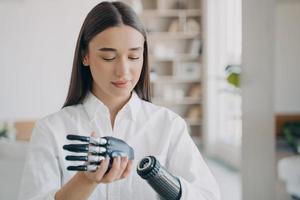 Disabled young woman is assembling bionic arm. Software and buttons, fingers and palm.