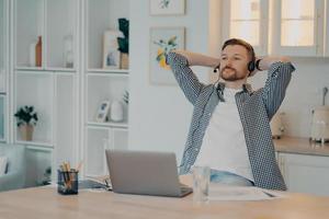 tranquilo joven autónomo descansando mientras está sentado en su lugar de trabajo en casa foto