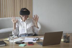 Excited businesswoman wearing virtual reality glasses while working in office photo