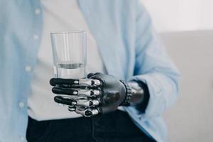 Morning routines of disabled person. Girl is holding glass of water with robotic arm prosthesis. photo